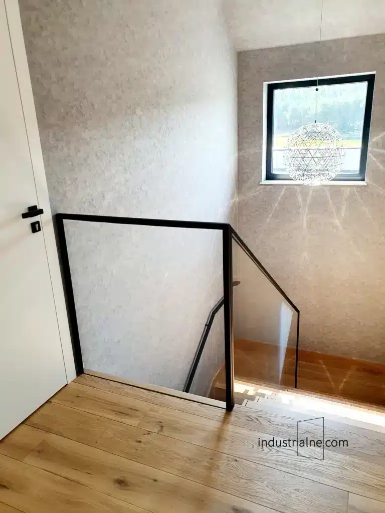Minimalistyczna balustrada szklana ze stalowym pochwytem przy drewnianych schodach w Wejherowie.