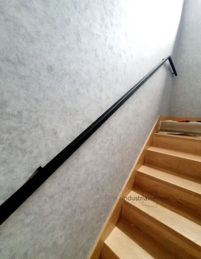 Detal czarnej poręczy schodowej ze stali na tle betonowej ściany w Wejherowie.