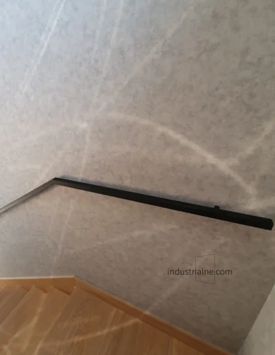 Czarna poręcz ścienna ze stali o nowoczesnej strukturze w minimalistycznym wnętrzu.
