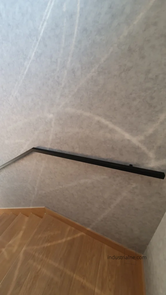 Czarna poręcz ścienna ze stali o nowoczesnej strukturze w minimalistycznym wnętrzu.